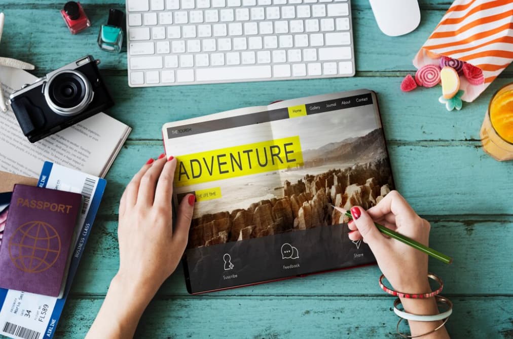 A person planning a trip with a tablet displaying "ADVENTURE"